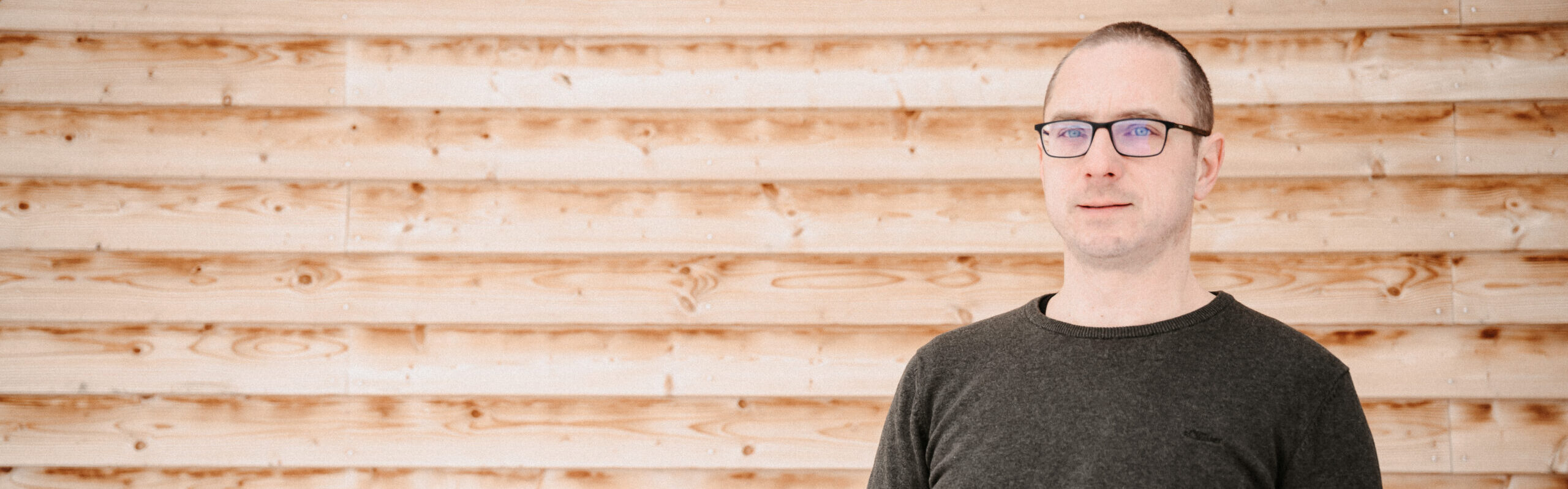 Porträt von Benjamin Mayr vor einer Holzwand