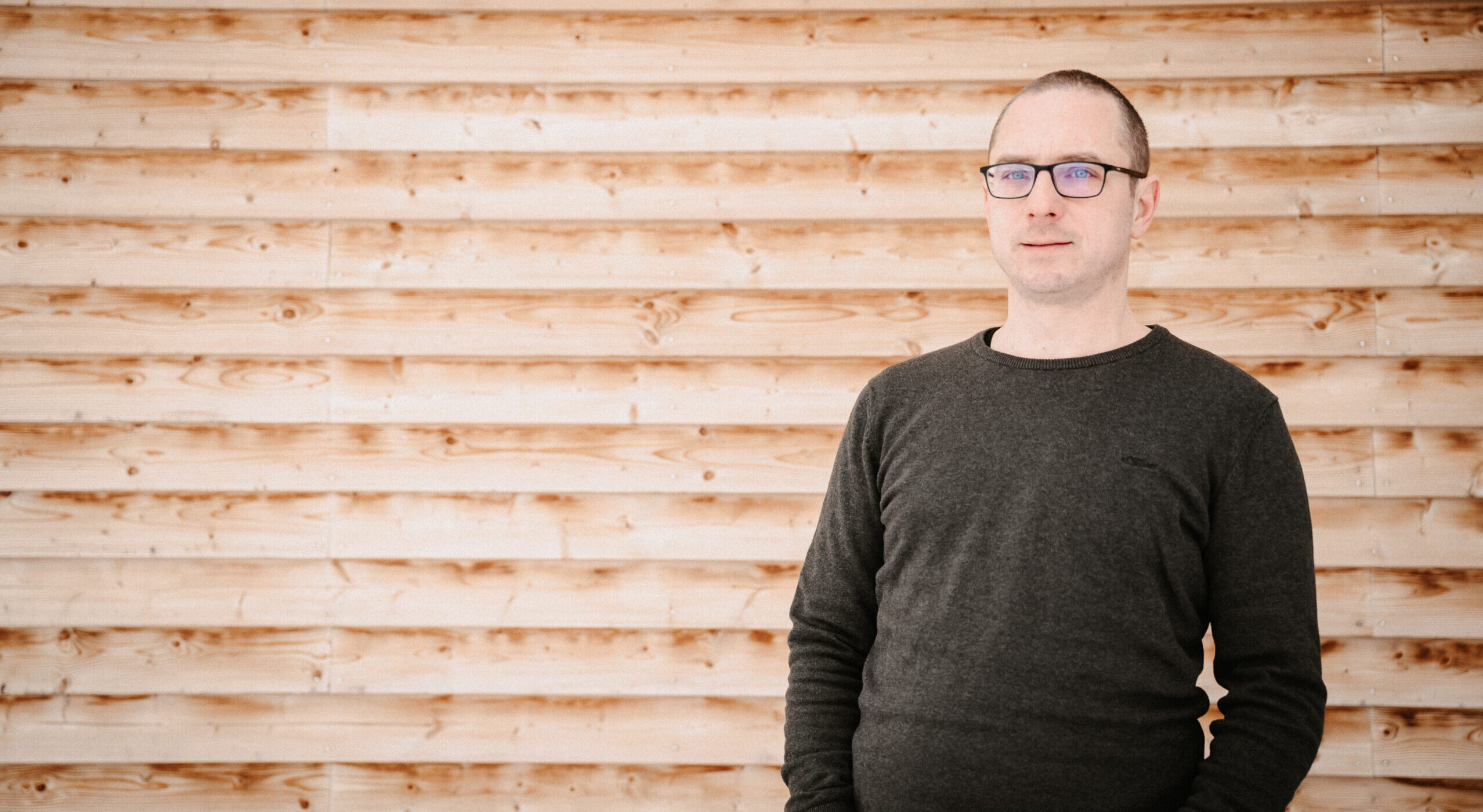 Porträt von Benjamin Mayr vor einer Holzwand